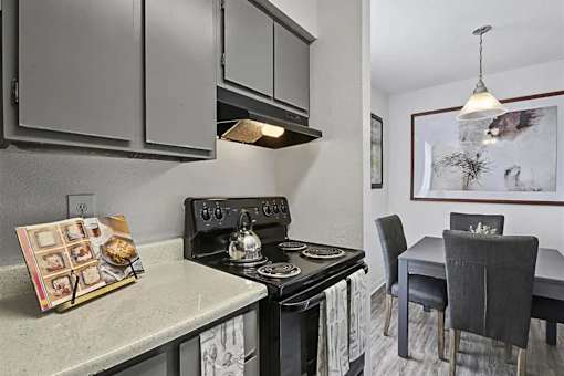 A kitchen with a stove, oven, and a dining table with chairs.