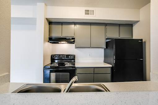 A kitchen with a black refrigerator and stove.