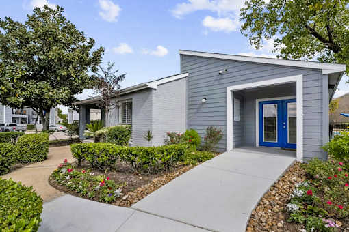 A small house with a blue door is surrounded by a garden.