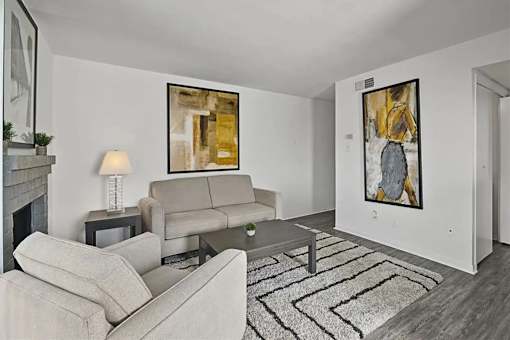 A living room with a grey couch, a coffee table, and a painting on the wall.
