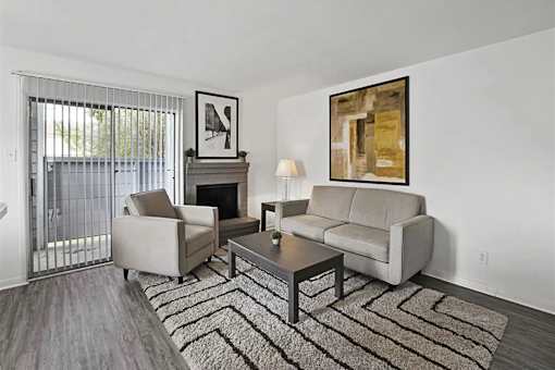 A living room with a grey couch, a coffee table, a fireplace, and a painting on the wall.