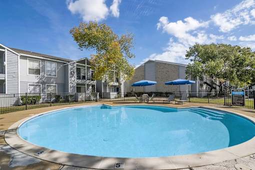 A swimming pool surrounded by a fence and trees.
