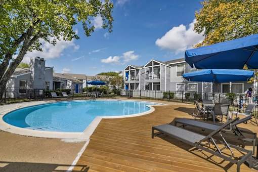 A pool surrounded by a wooden deck and chairs.