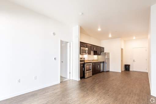A kitchen with white walls and wooden floors.