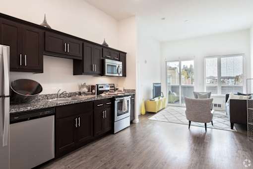 A kitchen with dark brown cabinets and a black fridge.