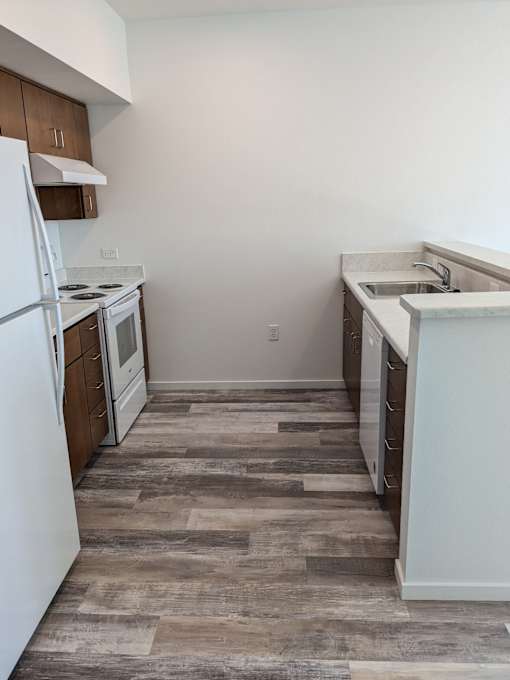 A kitchen with a white fridge, white countertops, and a white sink.