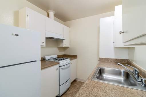 A kitchen with a white fridge, stove and sink.