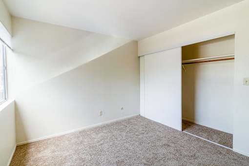 A room with a carpeted floor and a window on the left side.