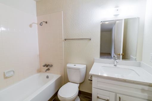 A white bathroom with a toilet, sink, and bathtub.