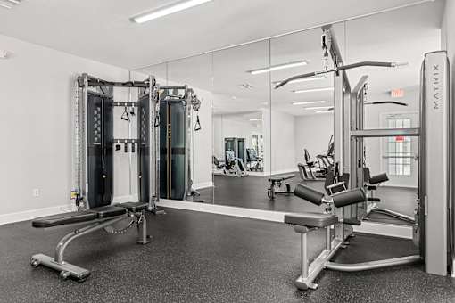 A gym with a mirror, a bench, and a weight machine.