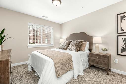 A bedroom with a bed, nightstand, and a plant.