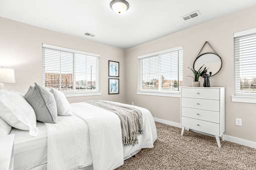 A bedroom with a white bed and a white dresser.
