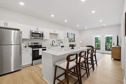 A kitchen with a white island and wooden chairs.