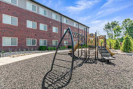 A playground with a slide and a building in the background.