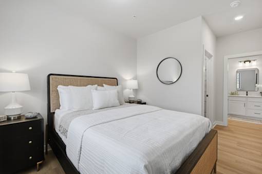 A bedroom with a large bed, a dresser, and a mirror.