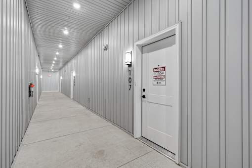 A long hallway with a door that has a sign on it.