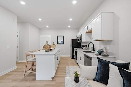A modern kitchen with white cabinets and a wooden floor.