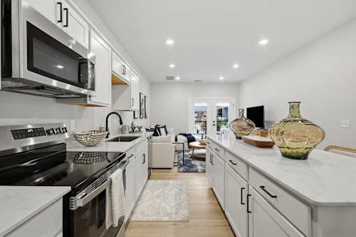 A modern kitchen with white cabinets and black appliances.