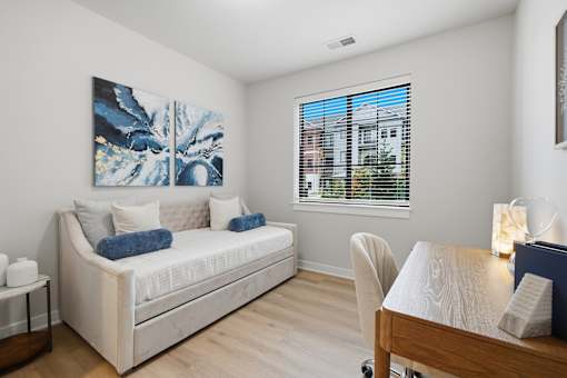 A living room with a white couch and a painting on the wall.