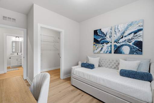 A bedroom with a bed, a chair, and a painting on the wall.