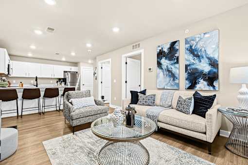 A modern living room with a glass coffee table and a grey sofa.