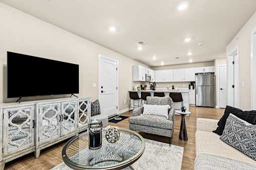 A modern living room with a glass coffee table and a television on the wall.