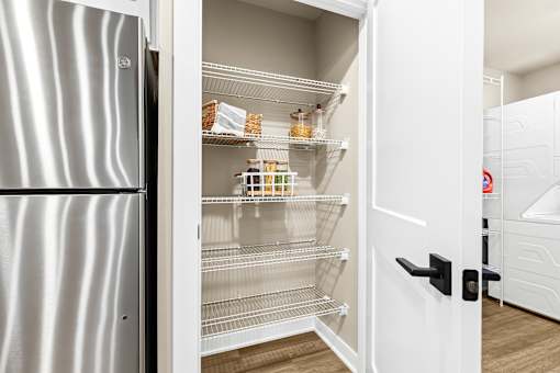 A modern kitchen with a white fridge and open empty drawers.