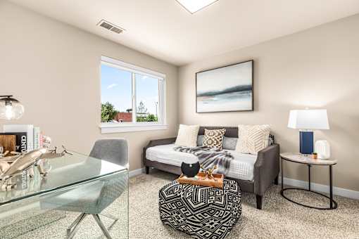 A living room with a glass table and a grey chair.