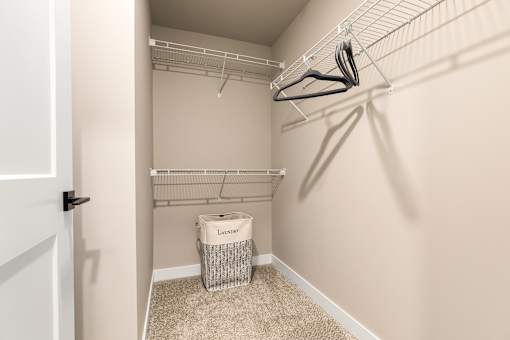 A laundry room with a white door, a white basket, and a white wall.