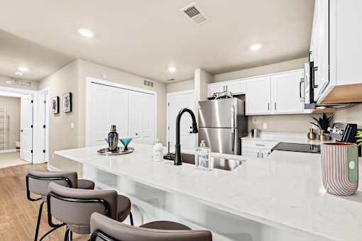 A modern kitchen with a white countertop and grey chairs.