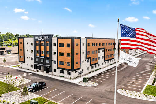 Sterling Center parking lot with a black truck and a large American flag.
