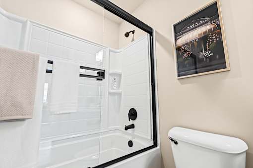 A white bathtub with a glass door and a towel hanging on the side.