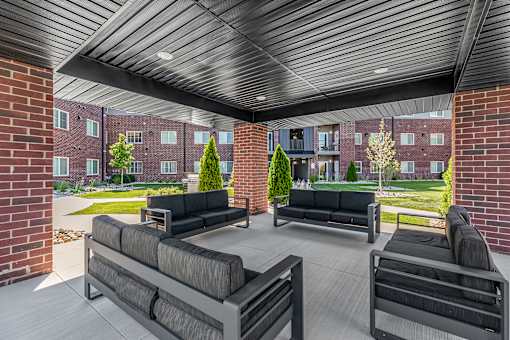 A patio with black couches and a wooden ceiling.