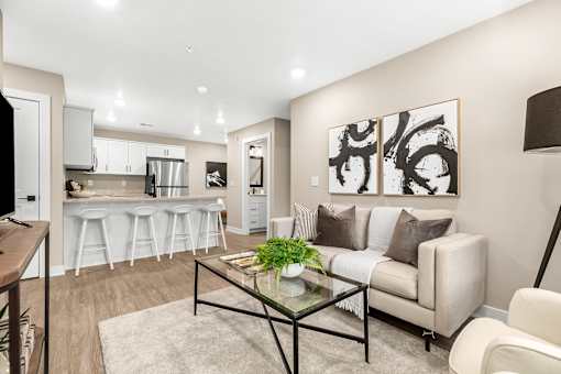 A modern living room with a glass coffee table and a couch with throw pillows.