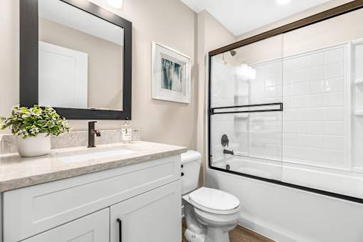 A white toilet sits in a bathroom next to a sink and a mirror.