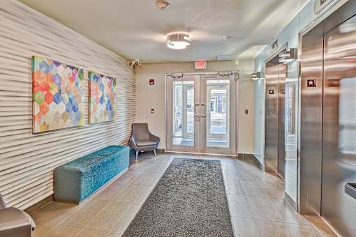 A hallway with a bench, a chair, and a painting on the wall.