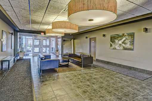 A spacious waiting area with a bench, a table, and a painting on the wall.