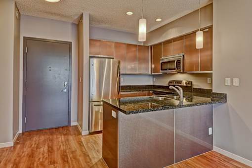 A kitchen with a refrigerator, microwave, and sink.