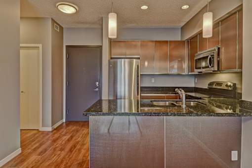 A kitchen with a granite counter top and stainless steel appliances.