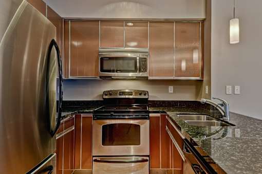 A modern kitchen with a stainless steel refrigerator and wooden cabinets.