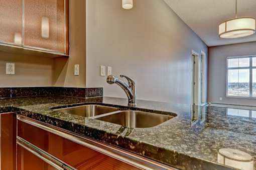 A modern kitchen with a granite countertop and stainless steel sink.