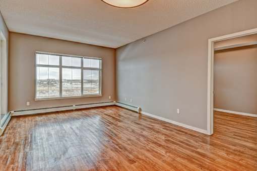 A room with wooden flooring and a large window.
