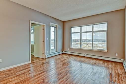 A room with wooden floors and a large window overlooking a parking lot.