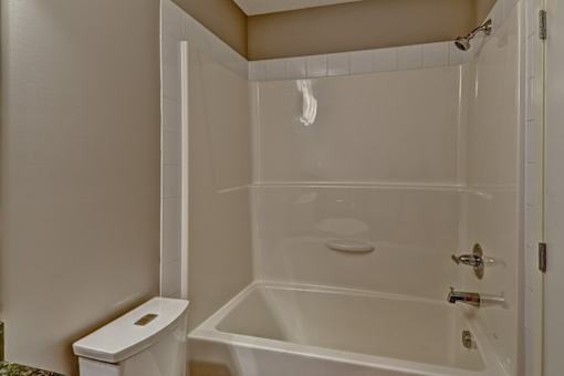 A white bathroom with a toilet, tub, and shower.