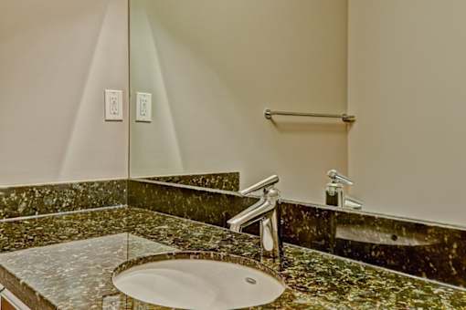 A bathroom with a marble counter top and a round sink.