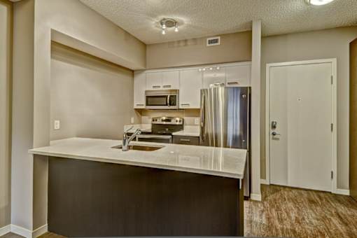 A kitchen with a refrigerator, microwave, and oven.