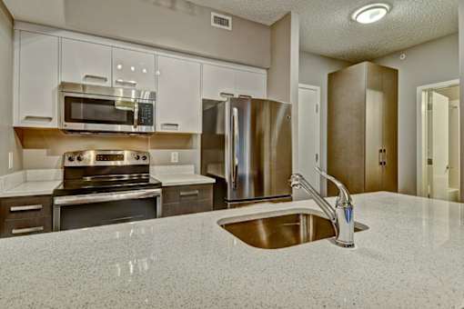 A kitchen with a sink, stove, and refrigerator.
