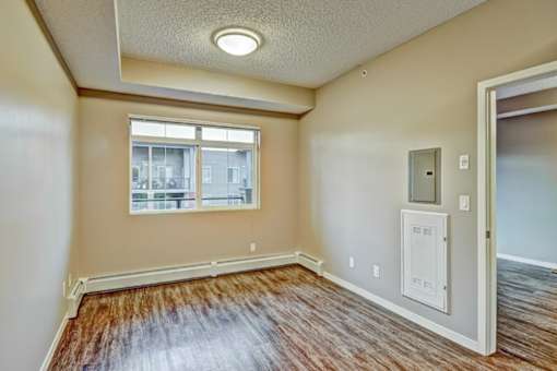 A room with a window and a white electrical box on the wall.