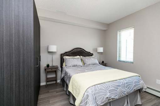 A bedroom with a large bed and a nightstand with a lamp.