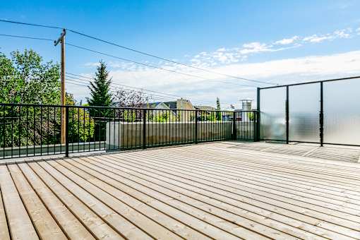 A wooden deck with a black fence and a clear blue sky.